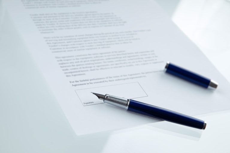 Ein Dokument auf einem Tisch, daneben ein Füller und ein blauer Stift.