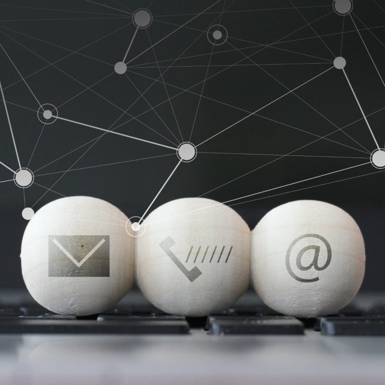 Drei Kugeln mit Symbolen für E-Mail, Telefon und @ auf einer Tastatur.
